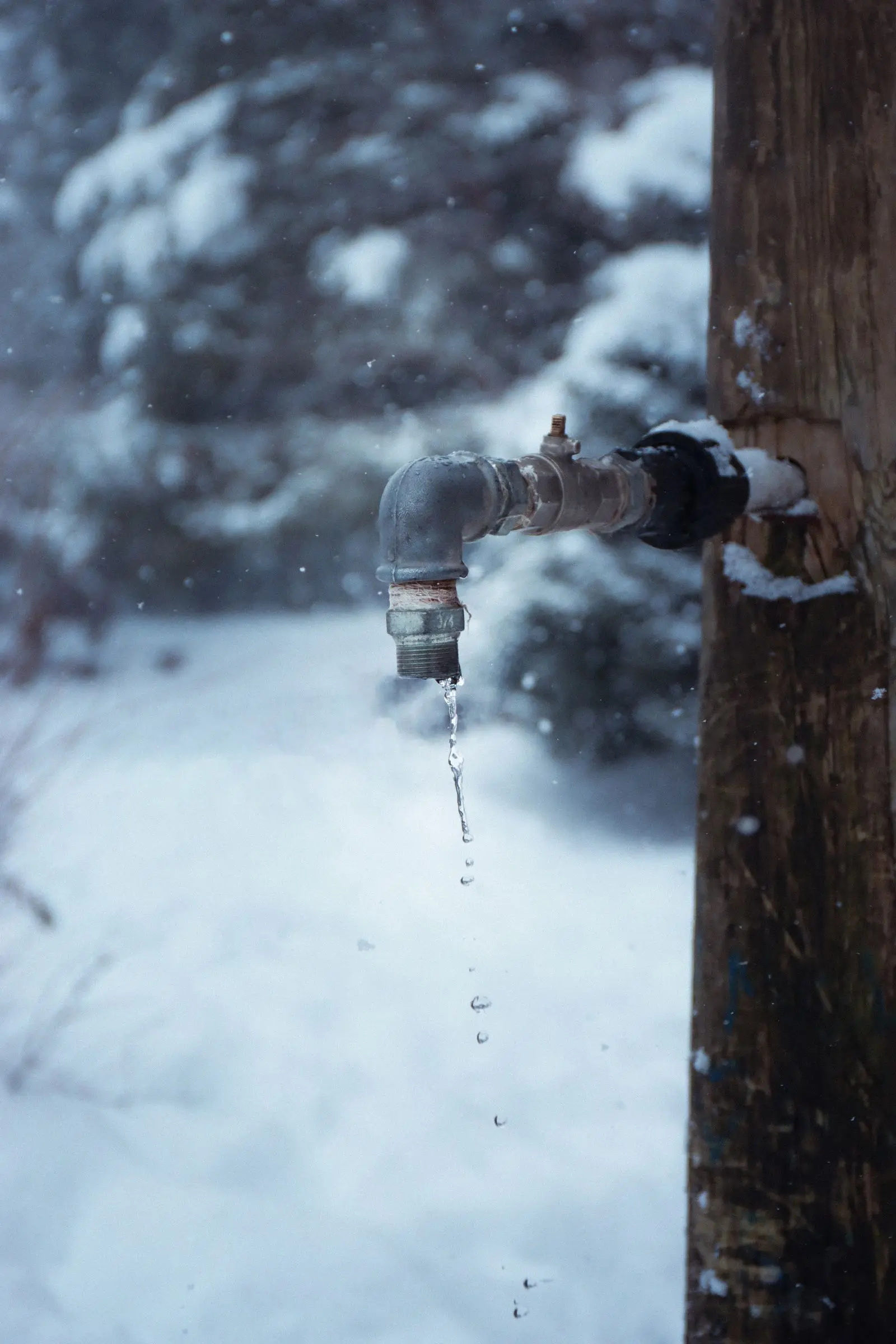 Outdoor faucet dripping with ice around it in winter